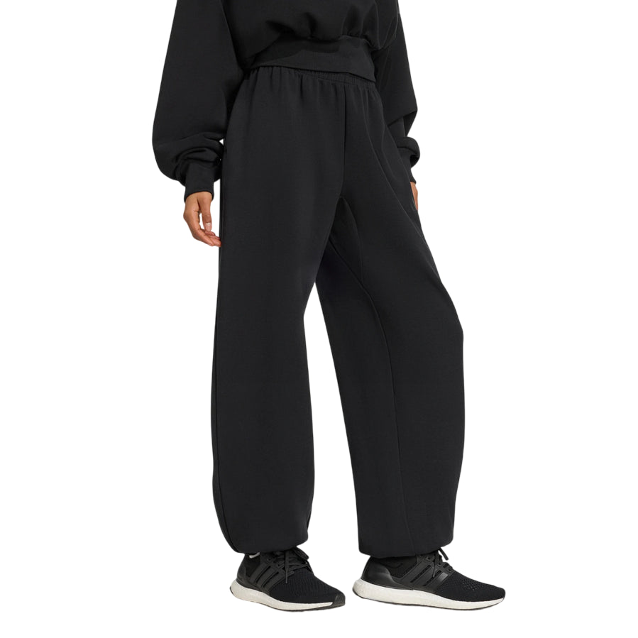 Vista laterale del pantalone Adidas donna nero, dettaglio della silhouette ampia e del tessuto spacer vellutato con modal